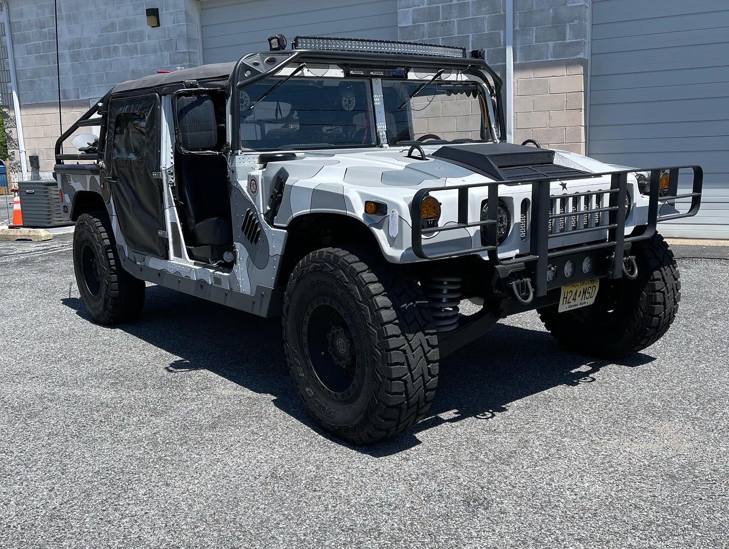 1990 AM General Humvee with camo wrap, featured in Off Road Xtreme, parked outside the Liquid Iron shop