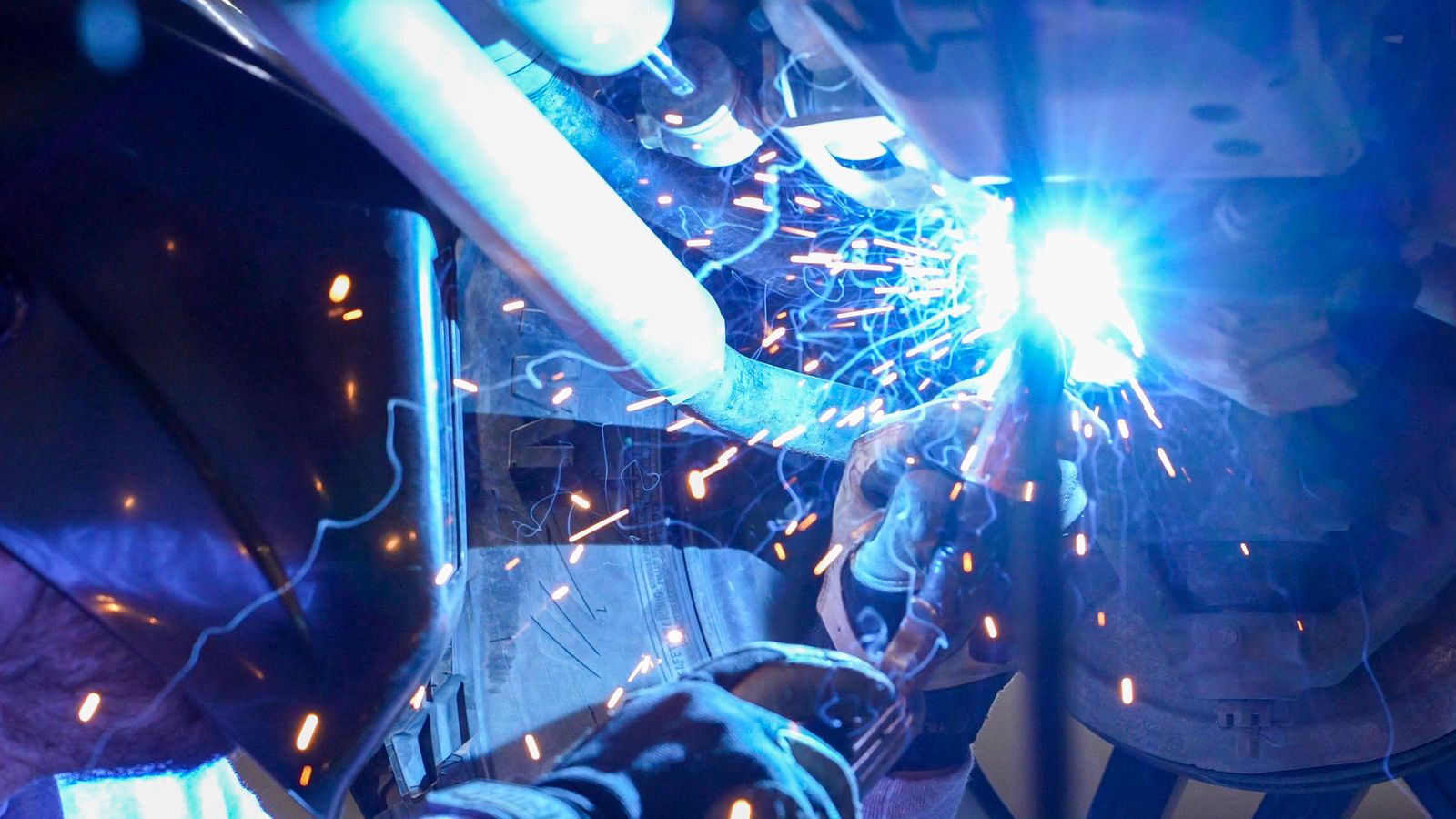 Liquid Iron technician welding a frame repair, sparks flying
