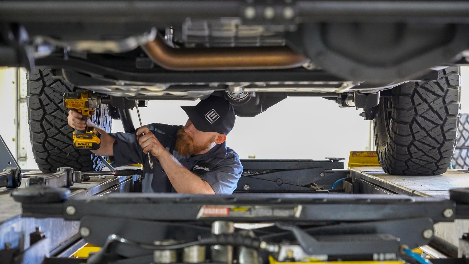 Liquid Iron technician working under a lifted vehicle with an impact driver